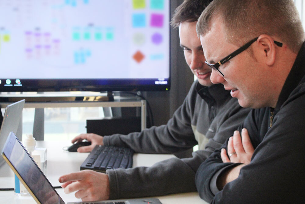 The Blueclaw team talking in the office, pointing at a laptop screen